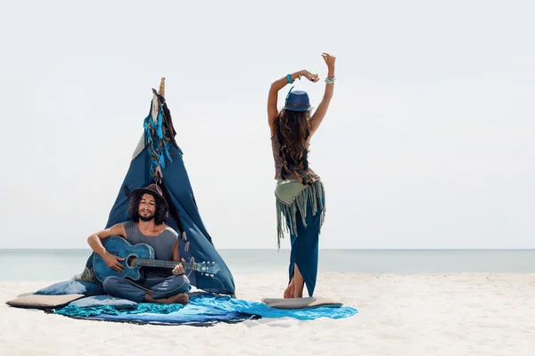 Homem tocando guitarra e menina dançando. Boho estilo casal em ser — Fotografia de Stock