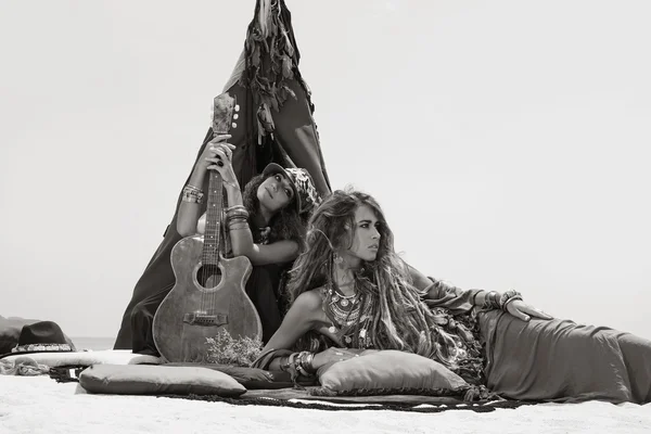 Two beautiful gypsy girls with guitar sitting on pillows at tepe ロイヤリティフリーのストック写真