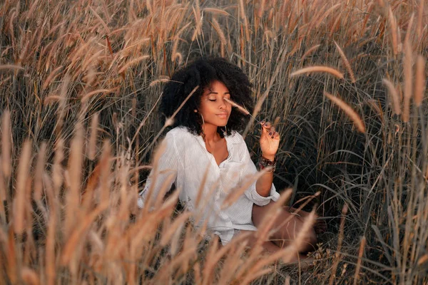 Attrayant jeune femme afro-américaine assis sur le terrain au coucher du soleil — Photo