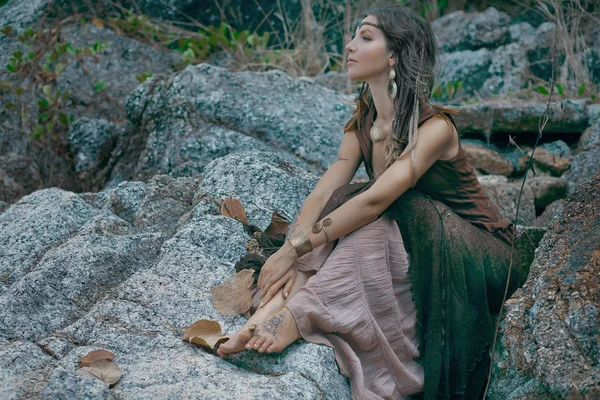 Beautiful young woman sitting on stone — Stock Photo, Image