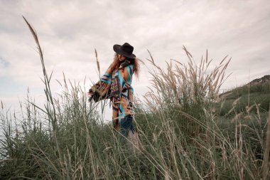 Panço yeşil sahada günbatımında giyen güzel boho kadın