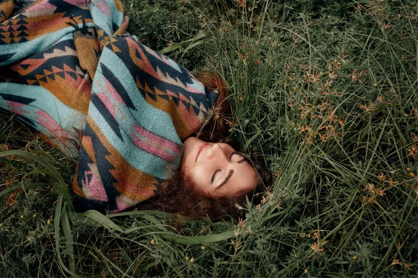 Mulher bonita boho vestindo poncho sentado no campo verde — Fotografia de Stock