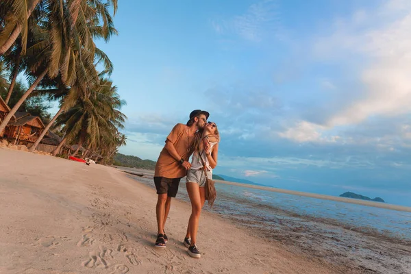 Feliz casal alegre andando na praia na hora do pôr do sol — Fotografia de Stock