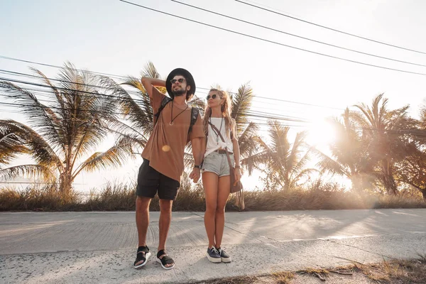Felice coppia allegra passeggiando lungo la strada sull'isola tropicale al tramonto — Foto Stock