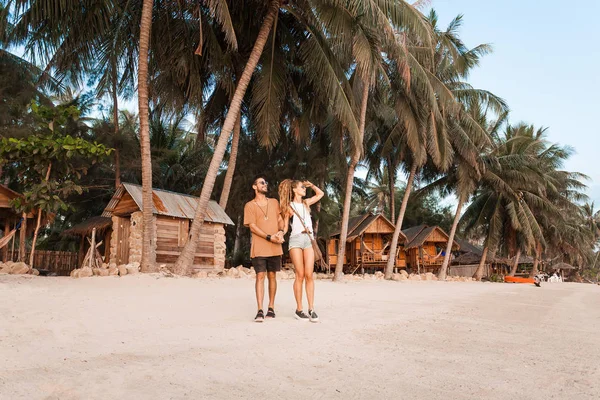 Glückliches, fröhliches Paar, das bei Sonnenuntergang am Strand spaziert — Stockfoto