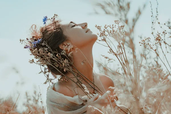 Hermosa joven con los ojos cerrados en un campo al atardecer — Foto de Stock