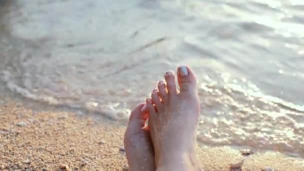 Vrouw voeten close-up op het strand bij zonsondergang — Stockvideo