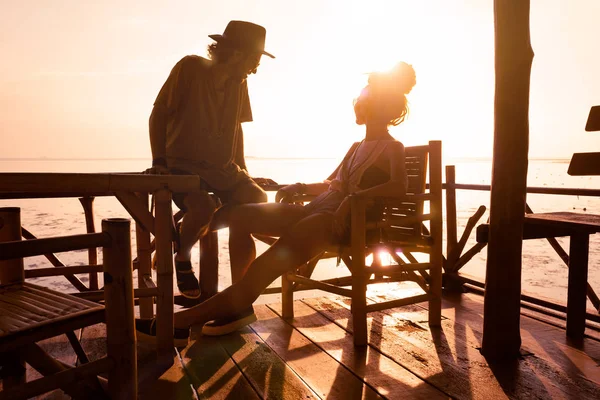 Silueta de joven elegante hombre y mujer sentado en alcoba al atardecer — Foto de Stock