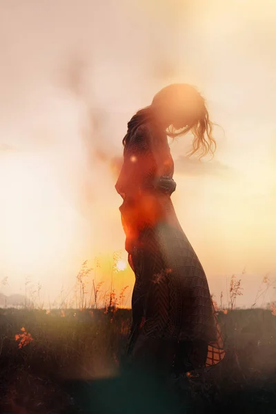 Silhueta de bela jovem mulher ao pôr do sol — Fotografia de Stock