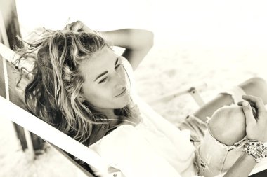 styllish genç güzel kadın giyim sandalyede tropik sahilde rahatlatıcı