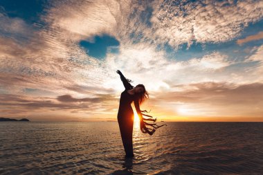 Zarif kadın suyun üzerinde dans etmek. Günbatımı ve yapısı.