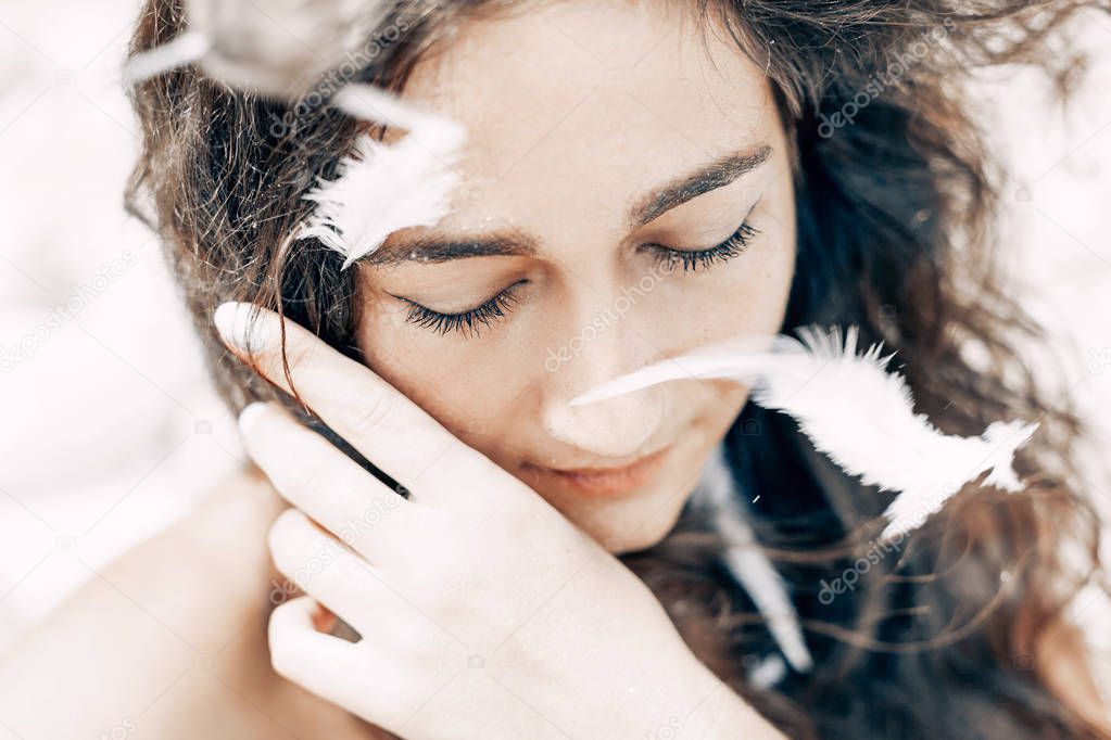 close up portrait of beautiful woman with white feathers