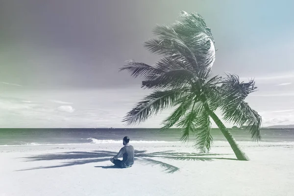 Άνθρωπος κάθεται στην παραλία κοντά από φοίνικα και να δούμε στον ορίζοντα l — Φωτογραφία Αρχείου
