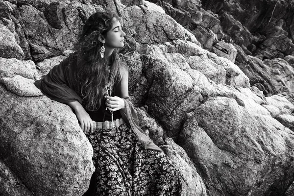 Piękna młoda kobieta siedzi na kamienie na zewnątrz — Zdjęcie stockowe