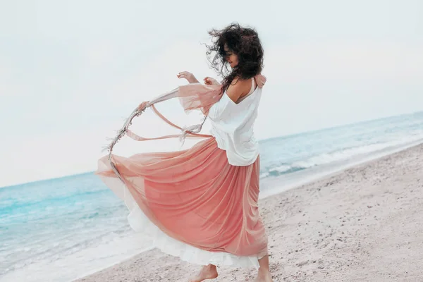 Vacker ung snygg kvinna i rosa kjol på stranden — Stockfoto