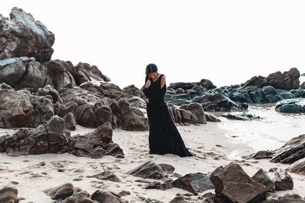 Κομψό νεαρή γυναίκα σε κομψό μαύρο φόρεμα για την παραλία με βότσαλα — Φωτογραφία Αρχείου