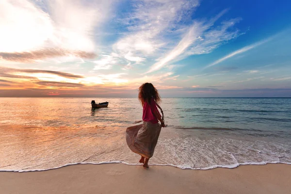 Veselá mladá žena baví na pláži při západu slunce — Stock fotografie
