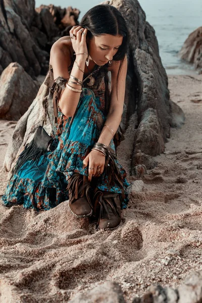 Boho styled young hippie girl sitting on beach at sunset — Stock Photo, Image