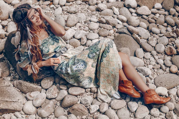 Joyeuse jeune femme à la mode assise sur la plage de pierre — Photo