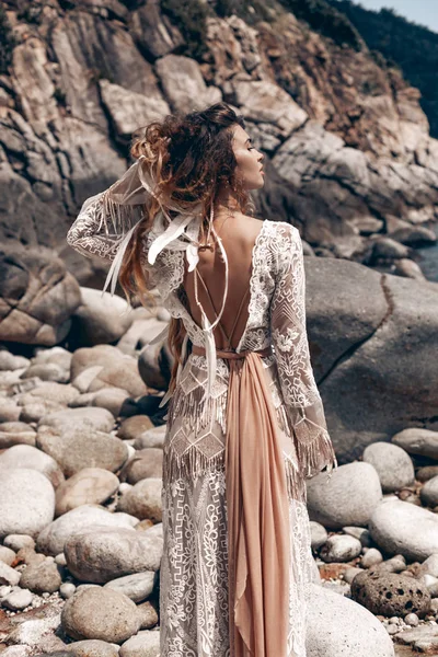 Fröhliche junge modische Frau sitzt am Steinstrand — Stockfoto