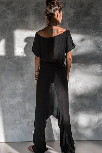 Молода жінка моди в чорній сукні позує на простому фоні — стокове фото