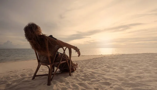 日落时年轻女子在海滩上的椅子上休息 — 图库照片