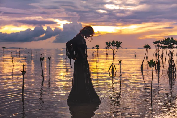 Young woman standing in water at sunset silhouette — Stock Photo, Image