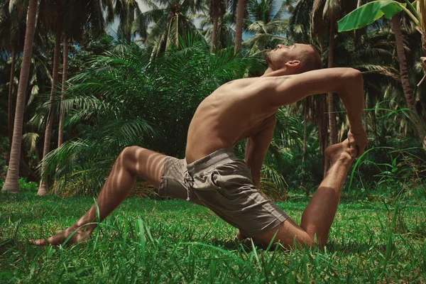 sporty man doing yoga in jungle