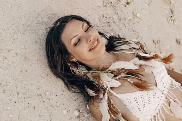 Hermosa joven boho mujer en vestido blanco y plumas posando en — Foto de Stock