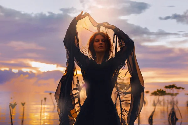Gün batımı siluet su içinde duran genç kadın — Stok fotoğraf