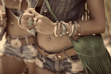 Kot giymiş, kumsalda birlikte poz veren bohem kadınların görüntüsü.