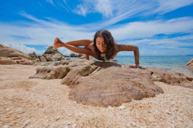 Genç sporcu kadın güzel sahilde yoga yapıyor.