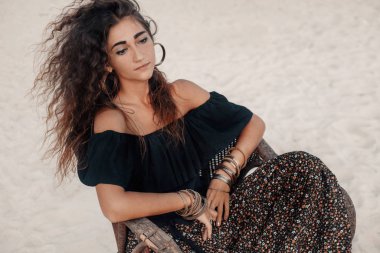 Kameraya poz veren bohem tarzı çekici genç bir kadın.