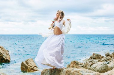 majestic bohemian girl in dress on stone beach