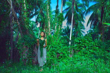 Genç ve güzel bir kadın çiçek kıyafetiyle doğaya poz veriyor.