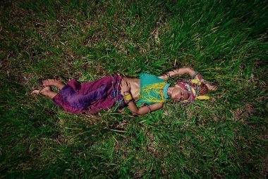 Moda fotografı. Türbanlı kadın çimenlerde yatıyor.