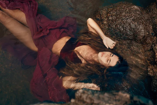 young attractive woman lying on rocks on sea beach