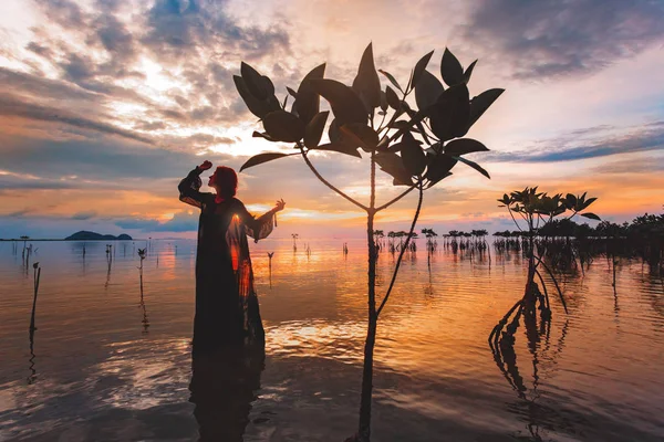 Joven mujer de pie en el agua al atardecer silueta — Foto de Stock