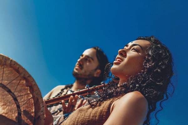 красивая молодая пара играет этническую музыку с шаманскими барабанами
 
