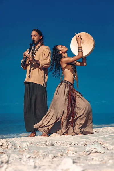 Belo jovem casal tocando música étnica com tambores xamã — Fotografia de Stock