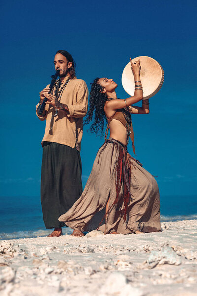 beautiful young couple playing ethnical music with shaman drums 