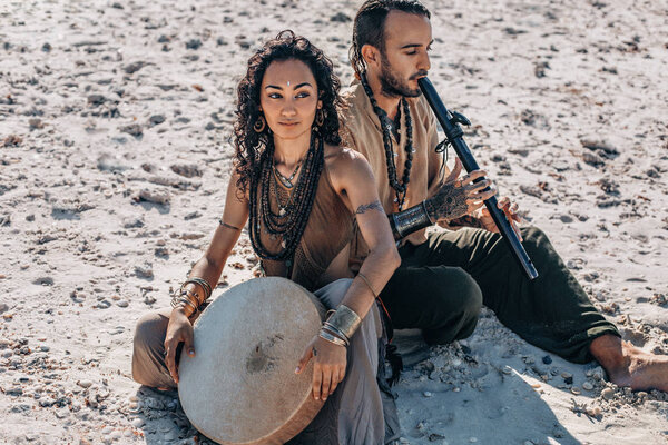 beautiful young couple playing ethnical music with shaman drums 