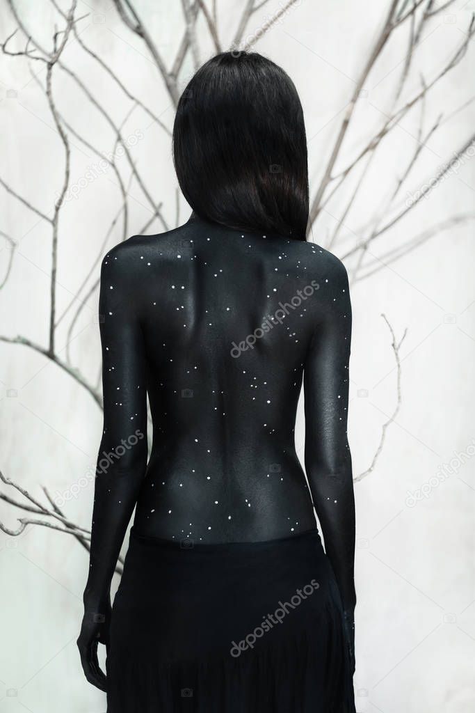 Mysterious woman in black body art portrait with branches background