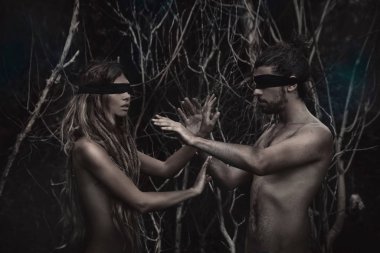 Gözleri kapalı, ormanda kavramsal poz veren çekici bir kadın ve erkek.