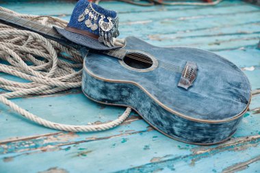 Gitar, eski mavi ahşap bir teknede, şapka ve iple yatıyordu.
