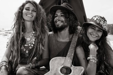 Çekici boho erkeği ve kadınlar çadırda yastıklarda oturuyor.