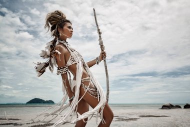 Amerikan yerlisi ve kumsalda poz veren çekici, vahşi bir kadın.