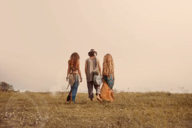 Çekici boho erkeği ve kadınlar sahada yürüyorlar.