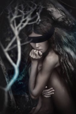 Genç, güzel, gözleri bağlı bir kadın karanlık ve ürkütücü bir ormanda.