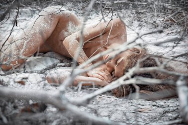 beautiful naked woman lying on dry crack ground in fetal position clipart